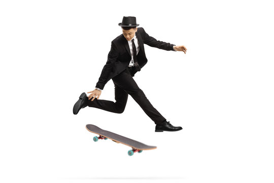 Young Man In An Elegant Suit Jumping With A Skateboard