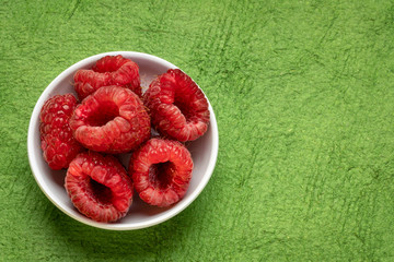 fresh red raspberries in a small ceramic bowl