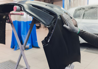 Auto mechanic preparing the car for paint job by applying polish with the power buffer machine