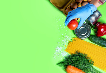 
Products for donation. Volunteer in blue gloves collects parcel. Green background.