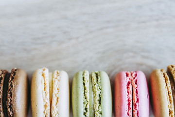 Macarons colorés alignés et arrière plan matière bois