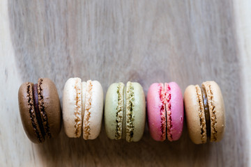 Macarons colorés alignés et arrière plan matière bois