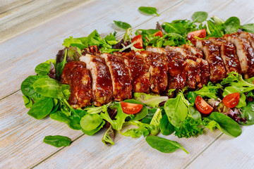 BBQ pork tenderloin on green leaves with tomato.