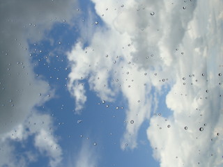 Rain drops on window glasses surface with cloudy background . Natural Pattern of raindrops isolated on cloudy background.