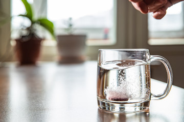 Sparkling tablet throw into a glass transparent glass, the glass is on a table, a pill for cold of...