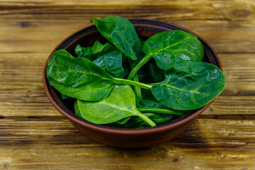 Fresh green spinach leaves in bowl on a wooden table