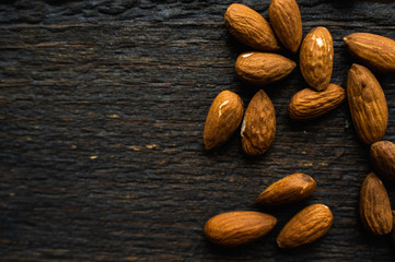 Almonds scattered on the wooden vintage table. Almond is a healthy vegetarian protein nutritious food. Almonds on rustic old wood.