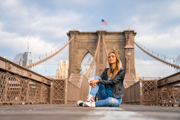 Young beautiful girl enjoying empty Brooklyn Bridge with a magical Manhattan island view.