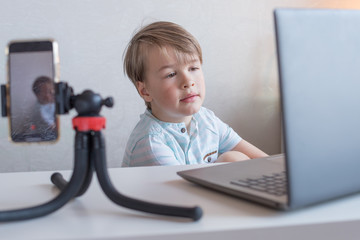 Cute european boy learns on-line at school the internet and laptop at home during quarantine. The concept of distance learning 