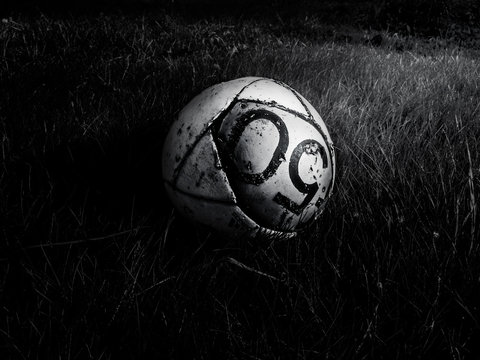 High Angle View Of Old Torn Soccer Ball On Grassy Field At Night