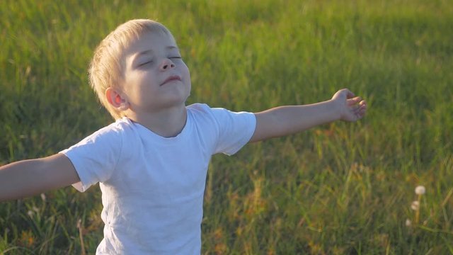 small child hands drawn to heaven concept happy family religion. little boy closed his eyes spread his arms to the sides on the nature in the park at sunset slow lifestyle motion video