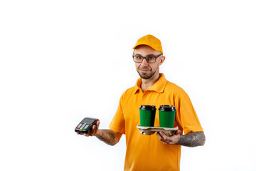 Friendly young man from a courier delivery service holds a beautiful green cup of coffee and a terminal for payment on a white background