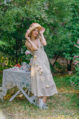 Obraz na płótnie Canvas Amazing girl in retro dress holding her flower hat. Dreamy scene at backyard of country house garden.
