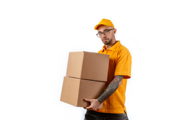 Friendly young delivery man holding big boxes in his hands on a white background