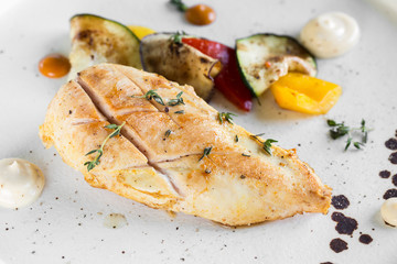 Grilled chicken breast served with baked vegetables. Close-up.