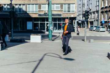 Young businessman walking with travel bag in the city .