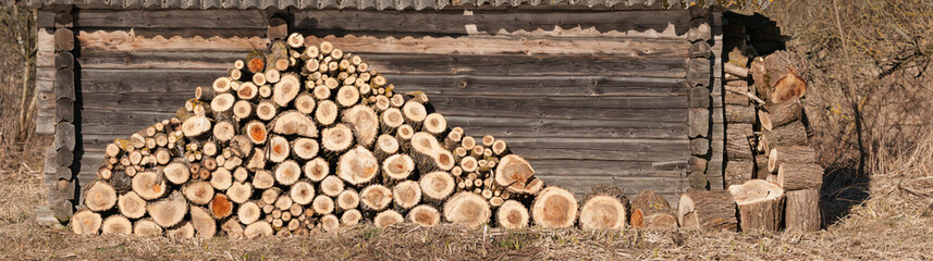 
logs stacked against a wooden wall, making up a beautiful composition.