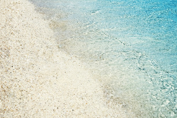 Fototapeta na wymiar Soft waves with foam of blue ocean on the sandy beach. Background.