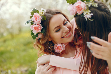Naklejka premium Pretty mother with daughter. Family in a spring park. Woman in a pink dress. Child with a flowers