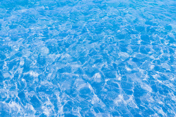 Blue clear water in the pool. Texture of water surface. Overhead view, Swimming pool bottom caustics ripple and flow with waves background.