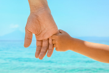 happy dad holds the hand of a child by the greek sea in nature