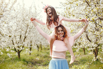 Pretty mother with daughter. Family in a spring park. Woman in a pink dress. Child with a flowers