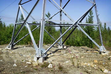 Legs of one of of steel lattice transmission tower mounted on rocky ground