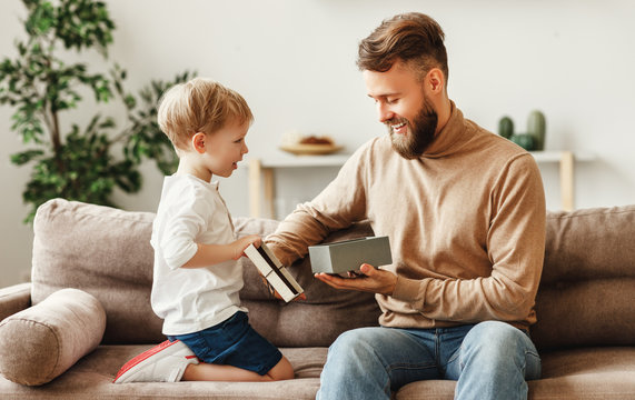 Happy Father Receiving Gift From Little Son At Home.