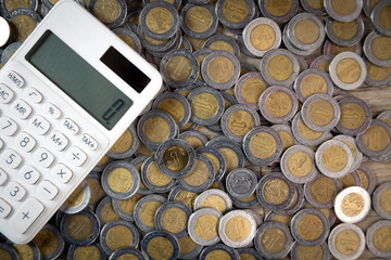 finance mexican coins in heap with shot from above with calculator at zero