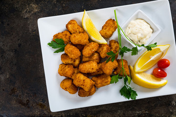 Crispy Fish Bites Snack Size. Deep Fried Codfish Fish Fingers with Tartar Dipping Sauce on Rustic Metal Background. Selective focus.