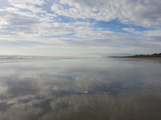Reflections of a cloudy sky on a calm beach landscape. Waimairi Beach, Christchurch.