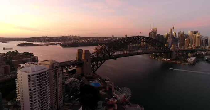 Sunrise in Sydney city over Harbour and major CBD landmarks the Sydney Harbour bridge in wide aerial panorama.
