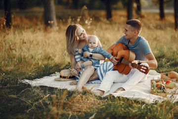 Family with cute little son. Father in a gray shirt. Family on a picnic. Man playing on a guitar