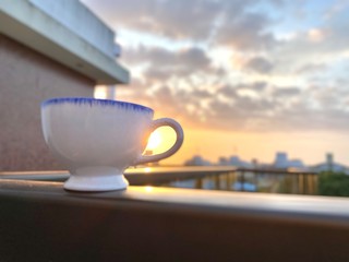 A cup of tea or coffee in the balcony. Sunrise. Yellow and clouded background