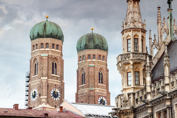 High twin towers of Gothic Frauenkirche cathedral and neo-Gothic new town hall building Neues Rathaus rise above roofs of historic main square Marienplatz, Altstadt Munchen Bayern Germany Europe