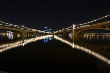 Converging bridges reflect in lake at night