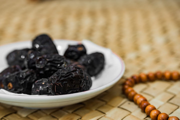 Ramadan food and drink in rural area or countryside concept. Muslim fasting. Dates fruits, prayer beads, drinking water on traditional mat.