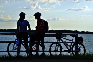 silhouettes of two cyclists on the countryside in the evening light