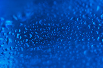 Water drops on the blue glass surface background
