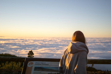 girl with sad gesture observes the sea of clouds from the teide volcano at sunset