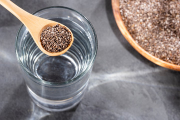 Spoon with organic chia seeds and glass of filtered water - Salvia hispánica
