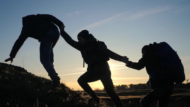 teamwork help business three men hold hand travel silhouette concept. group of tourists lends a helping hand climb the cliffs mountains. people climbers climb lifestyle to the top overcoming teamwork