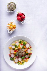 mixed salad on a white tablecloth surrounded by some ingredients
