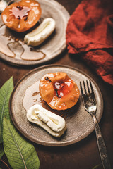 Turkish traditional dessert with sweet quince boiled in sugar syrup, spices and heavy cream Kaymak on ceramic plates over rusty brown table background, selective focus. Turkish national cuisine