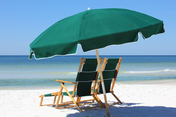 Two chairs and green umbrella on white sand beach