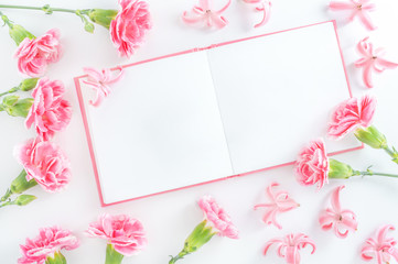 Notepad with space for text and pink flowers on white background. Top view with copy space.