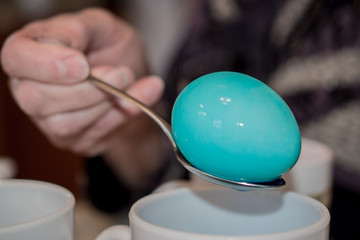 Dying Easter eggs tradition background. Blue bright Easter egg on a spoon background. Blue colorful...