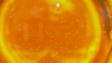 Macro close up floating orange syrup bubbles background. Corn syrup thickener and sweetener ingredient. Product and commercial uses in food preparation