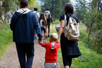 Fototapeta premium family for a walk in the mountains. Mother, father and to child going for a walk in mountain surroundings. Family adventure