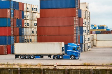 Cargo containers stack, semi truck in an intermodal shipping hub, container terminal